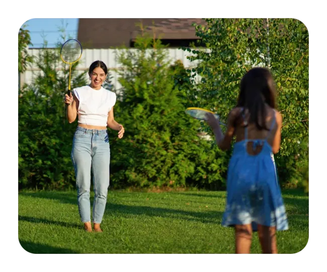 Mother and daughter playing outside on green healthy lawn
